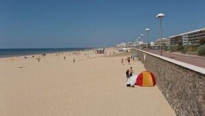 Une plage avec un mur de pierres et une rangée de bâtiments en arrière-plan.