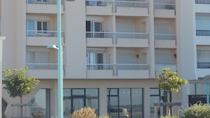 Un immeuble à plusieurs étages, doté de balcons, de grandes fenêtres et d’un lampadaire.