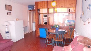 Une pièce chaleureuse avec une table à manger en bois, des chaises, un buffet bleu et un canapé rouge.