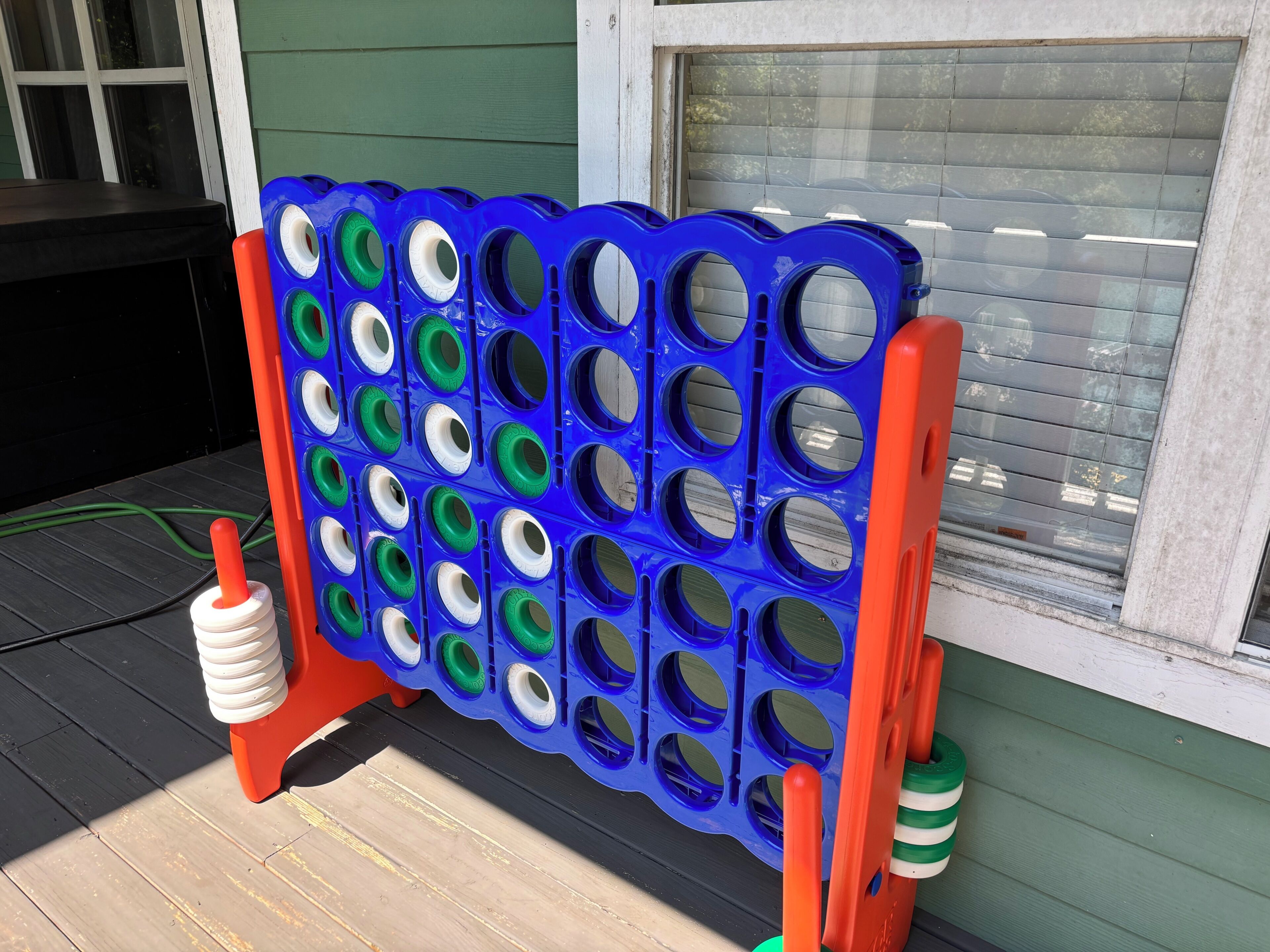 A blue and orange game board with multiple holes, positioned on a wooden deck.
