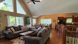 A spacious living room with a large sectional sofa, a dining area with a wooden table and chairs, and a kitchen with wooden cabinets and a black refrigerator. - Rock of Ages-- Huge Dock w/ 2 Covered Slips & Slide; Great House for Holidays! (LaFollette)