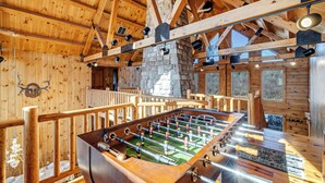 Ein Raum mit Holzboden, einer Kicker-Tischfußballanlage, einer Steinwand und Holzbalken.