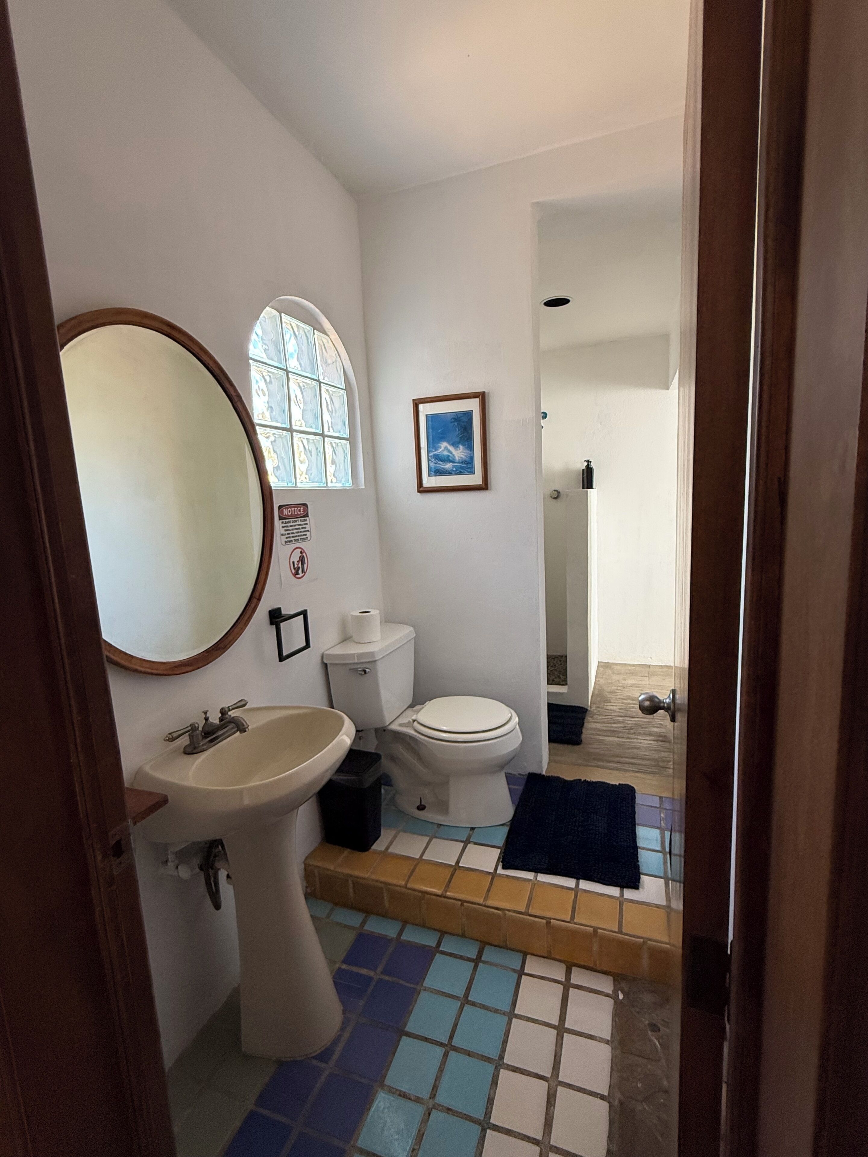 A bathroom with a sink, toilet, and mirror.