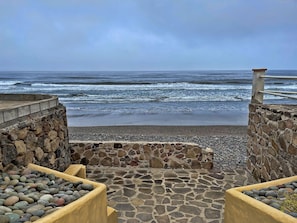Stroll along the oceanfront walkway, bordered by planters and stone walls, leading to the beach.