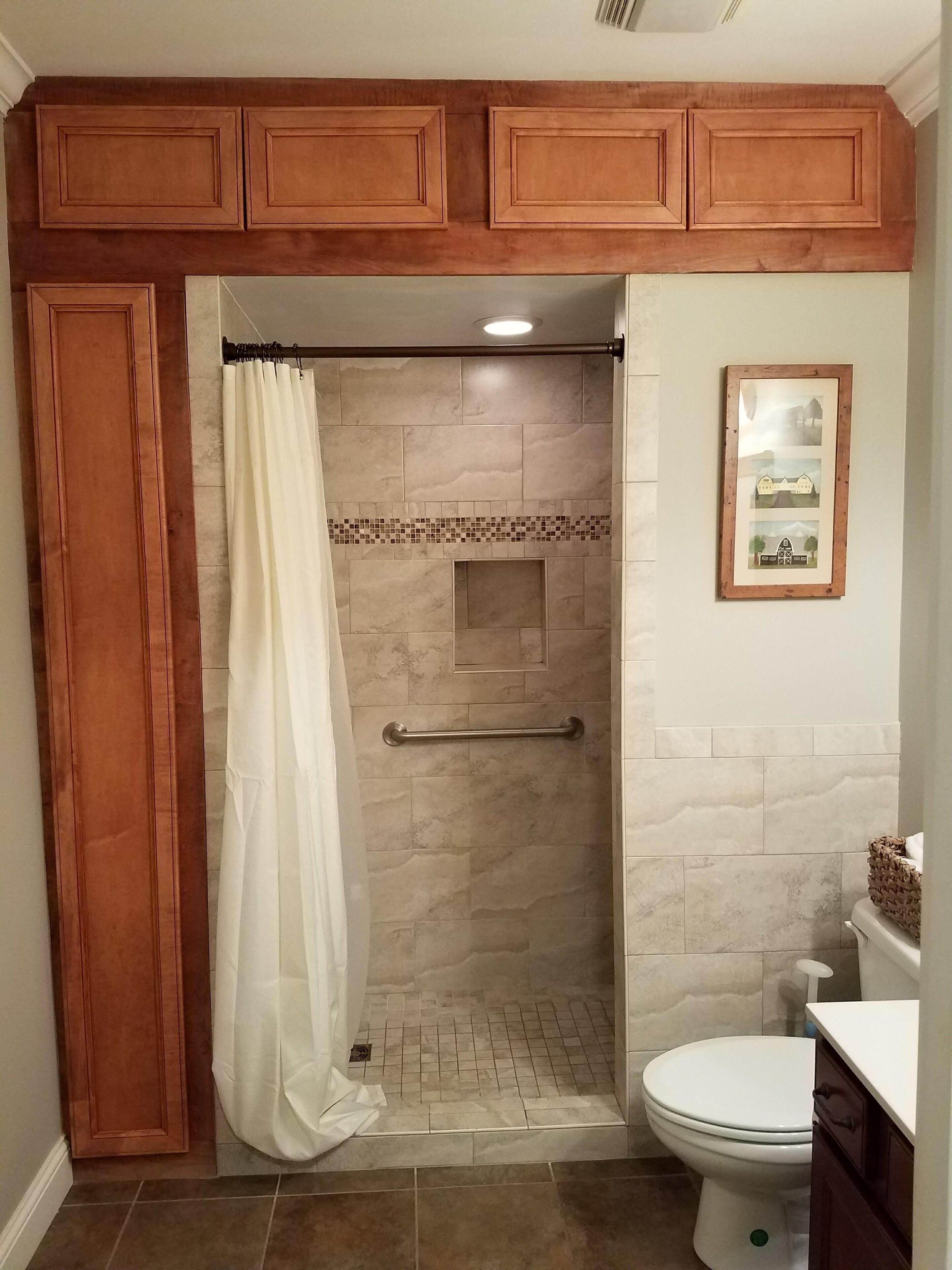 A bathroom with a shower, toilet, and wooden cabinets.