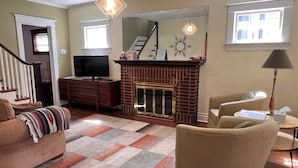 A living room with a fireplace, a television, a sofa, and a chair.