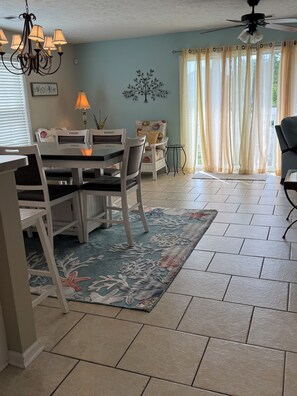 A dining area with a chandelier, a table with chairs, a decorative rug, and a ceiling fan. - Feels like home! This spacious & cozy beach house is a short walk to the beach!  (Surfside Beach)