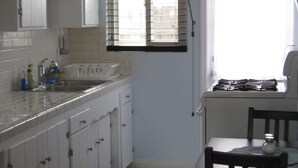 Una cocina con armarios blancos, un fregadero y una ventana con persianas.