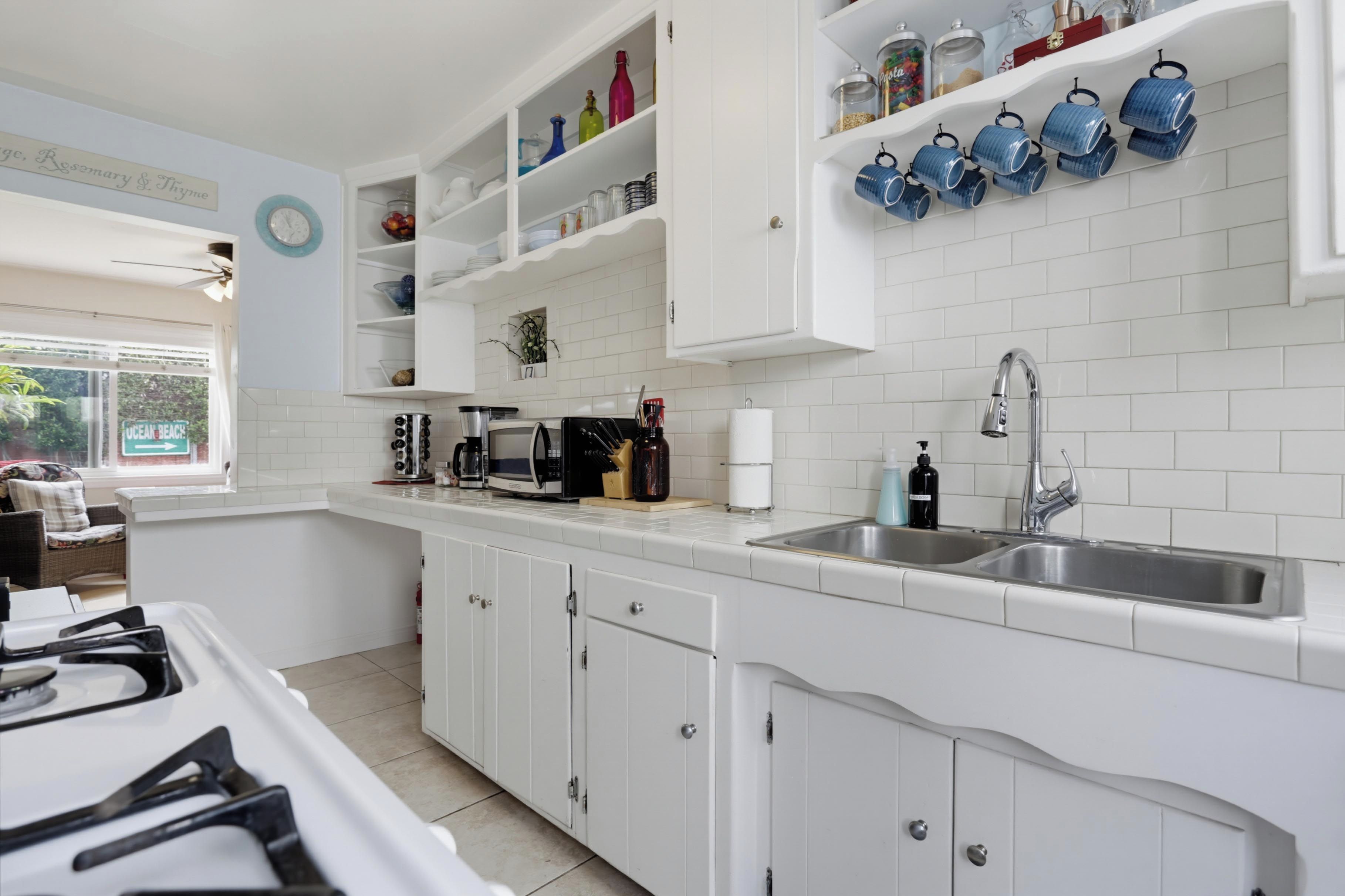 A kitchen with white cabinets, a double sink, and various kitchen appliances.
