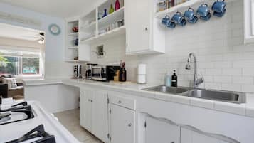 A kitchen with white cabinets, a double sink, and various kitchen appliances.