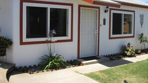 Una casa de una planta con fachada roja y blanca, una puerta principal y un pequeño porche.
