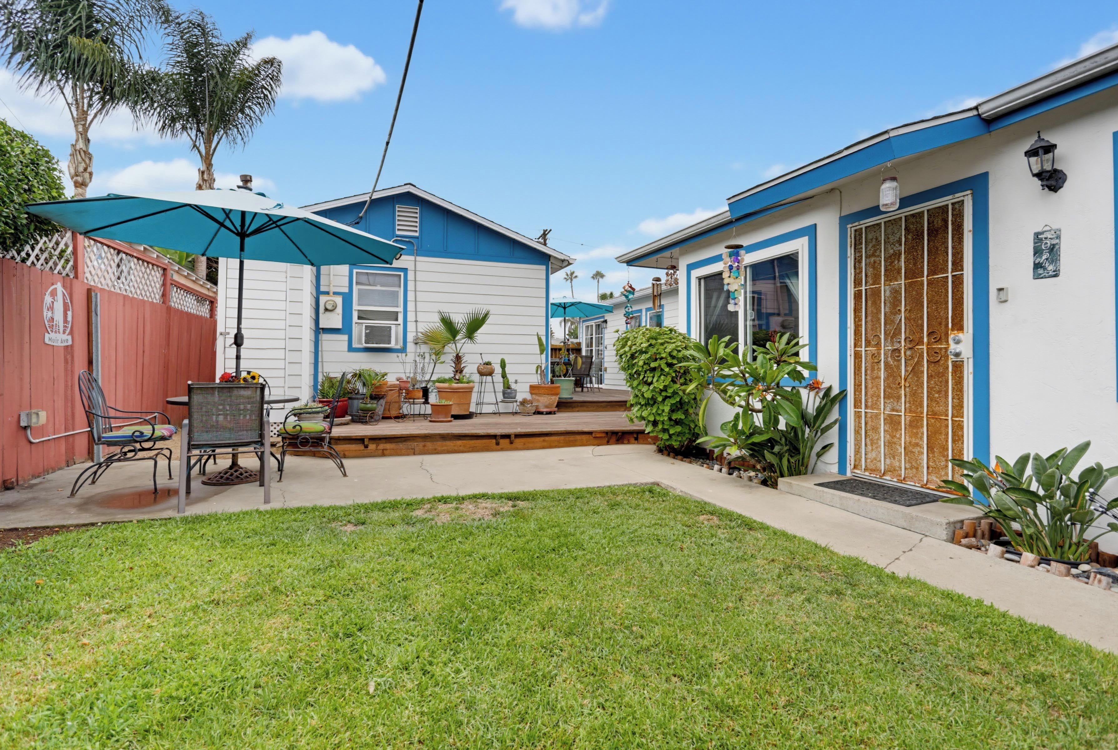 A residential property with a fenced backyard, outdoor seating, and potted plants.