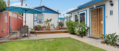 A residential property with a fenced backyard, outdoor seating, and potted plants.