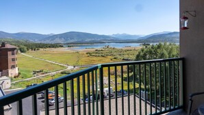 Ein Balkon mit Blick auf einen See, Berge und einen Parkplatz.