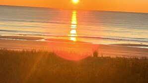 Un atardecer sobre una playa, con el sol reflejándose en el agua.