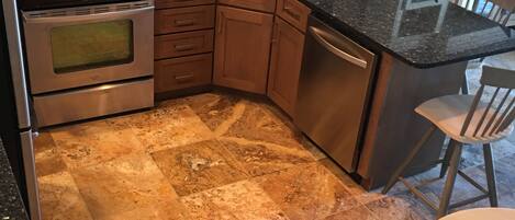 A kitchen with a microwave, stove, sink, and tiled backsplash.
