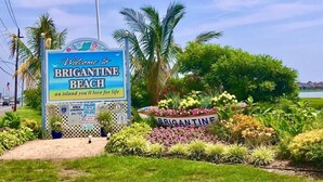 Un cartel de bienvenida a Brigantine Beach, con un jardín al frente.