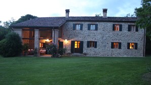 A stone house with a large front porch and multiple windows.