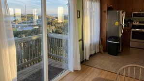 Una cocina con armarios de madera, un refrigerador de acero inoxidable y vistas a una zona residencial a través de amplios puertas corredizas de vidrio.