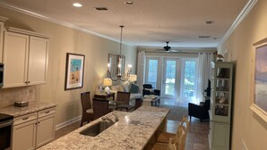 A spacious kitchen with granite countertops, a built-in sink, and a dining area with a long table and chairs.