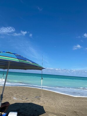 A beach with a colorful umbrella and a fishing rod. - Ocean Village Vacation Rental, Golf view. Short walking distance to the beach.  (Hutchinson Island)