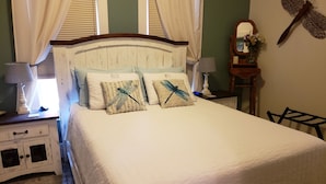 A neatly made bed with a white comforter and two decorative pillows featuring dragonfly designs.