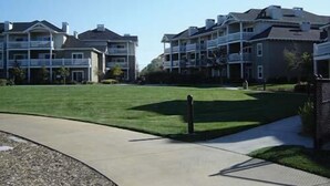 A residential complex with multiple two-story buildings, a well-maintained lawn, and a curved pathway. - Sip, Taste, Hot Tub, Repeat - Full Resort Access - Sleeps 6 (Windsor)