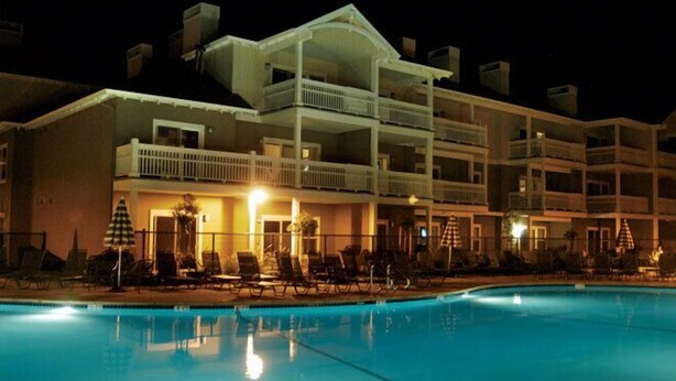 A multi-story hotel with balconies, a swimming pool, and lounge chairs. - Sip, Taste, Hot Tub, Repeat - Full Resort Access - Sleeps 6 (Windsor)