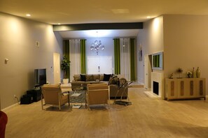 Ein modernes Wohnzimmer mit einer Couch, Sesseln, einem Couchtisch und einem Fernseher.