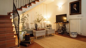 Una sala de estar con escalera, sofá, televisor y radiador.