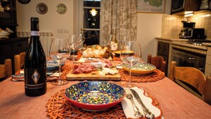 Una mesa de comedor servida con una botella de vino, copas, platos y cubiertos.
