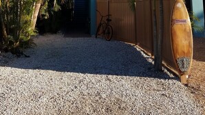 A modern house with a teal exterior, a wooden gate, and a surfboard in the driveway.