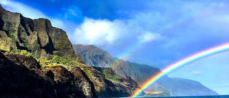A coastal landscape with a mountain and a rainbow over the sea.