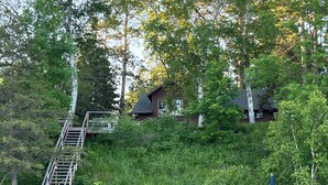 Un molo di legno che conduce a una casa con veranda e area salotto esterna.