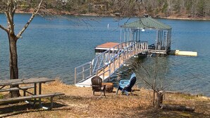 Un muelle a orillas del lago con una zona de estar cubierta y una mesa de picnic.