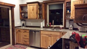 Una cocina con armarios de madera, lavavajillas, estufa y diversos electrodomésticos.
