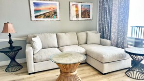 Ein modernes Wohnzimmer mit einer Eckcouch, zwei gerahmten Bildern, einem runden Couchtisch und einer Lampe.