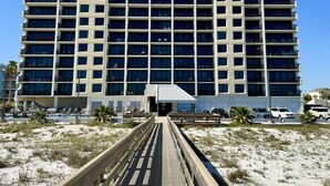 Ein mehrstöckiges Hotel mit zentralem Eingang, einer überdachten Galerie und einem Poolbereich im Vordergrund.