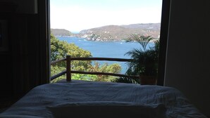 Ein Bett mit Blick auf eine Küstenlandschaft durch ein Fenster.