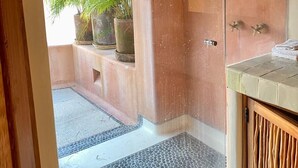 Ein Badezimmer mit Glasdusche, Holzwaschbecken und Topfpflanzen.