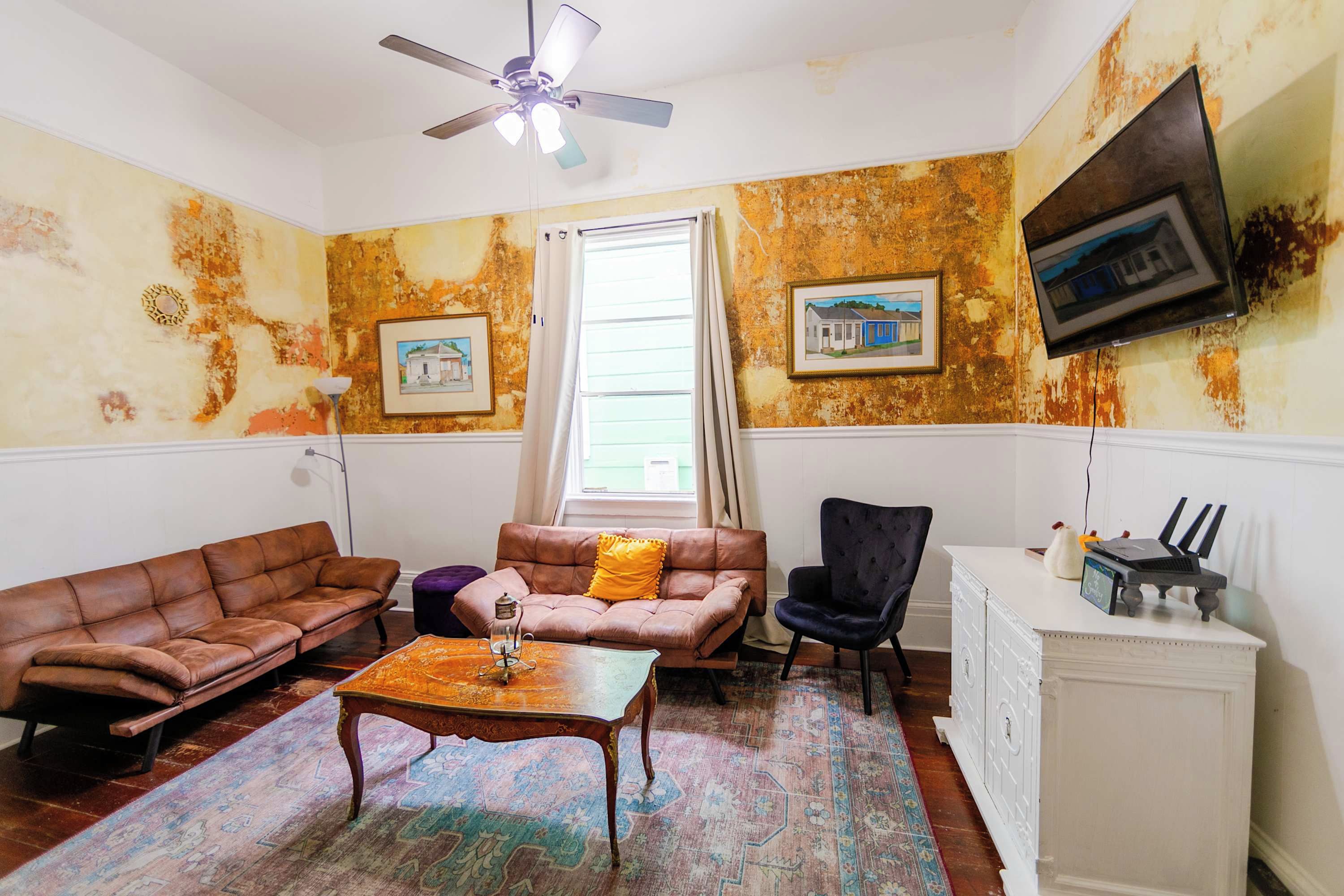 A living room with a brown leather sofa, a coffee table, a black chair, a white cabinet, and a ceiling fan.