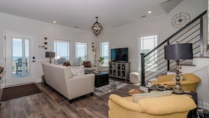 A spacious living room with a large sofa, a television, and a staircase. - e2 sunrise point (Myrtle Beach)