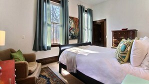 A bedroom with a large bed, a wooden wardrobe, and a window with curtains. - Big Blue House - Lower Unit - Near Forsyth Park - Sleeps 8 (Savannah)