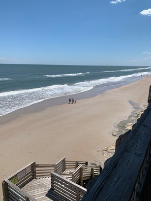 Ein Strand mit einer Holzpromenade, die zum Ufer führt.
