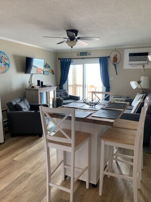 Ein gemütliches Wohnzimmer mit Essbereich, Deckenventilator, Fernseher und einem Papagei an der Wand.