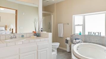 A bathroom with a sink, toilet, and bathtub. There is a window with the word "BEACH" on it.
