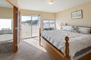 Quarto com uma cama grande, banheira e vista para a praia.