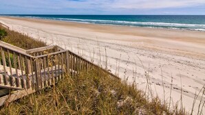 A beach with a wooden staircase leading down to the shore. - Best Views on the Island! Oceanfront, Sunsets, Boat dock, Elevator, pool, fish! (Topsail Beach)