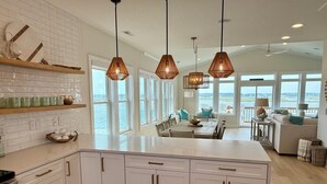 A spacious kitchen with white cabinetry, a large island, and pendant lighting. - Best Views on the Island! Oceanfront, Sunsets, Boat dock, Elevator, pool, fish! (Topsail Beach)