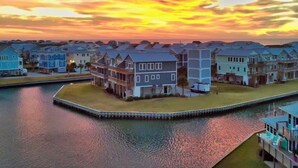 A waterfront residential area with houses along a canal, featuring a dock and a pier. - Best Views on the Island! Oceanfront, Sunsets, Boat dock, Elevator, pool, fish! (Topsail Beach)